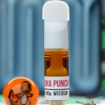 Banana Punch 1g rosin cartridge photographed with Dank Tank studio props and amber rosin oil